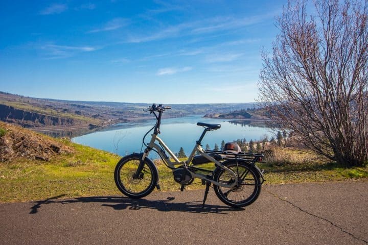 Electric bike on a path overlooking a scenic lake and hills under a clear blue sky.