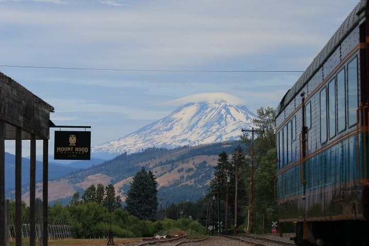 Train station with Mount Hood in background and a vintage railcar on the right.
